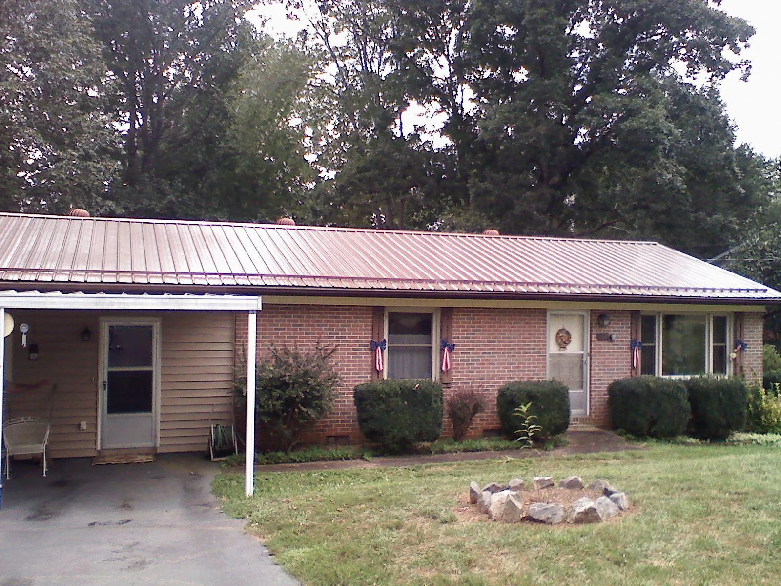 Bronze metal roof and carport on a brick ranch home — Roof Repair work by our crew in Perry