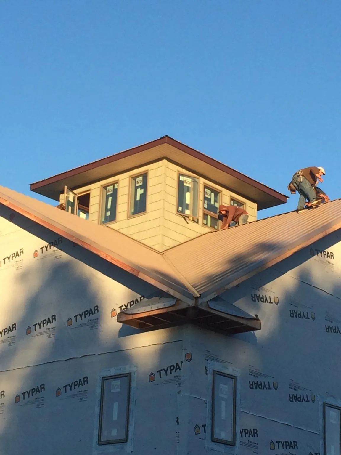 Roofers working around a rooftop cupola on a new metal roof at sunset — Roof Waterproofing in Perry by Roofing Brothers